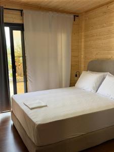 a bedroom with a large white bed with a window at Paradise Beachfront Chalet Rooms Borsh in Borsh