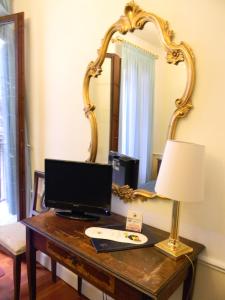 a desk with a monitor and a lamp and a mirror at Hotel Pantalon in Venice