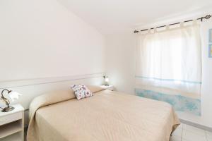 a white bedroom with a bed and a window at Vista Corsica in Isola Rossa