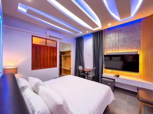 a bedroom with a large bed and a flat screen tv at เซฟเฮ้าส์ รีสอร์ท in Pattani
