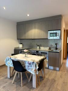 a kitchen with a table with chairs and a stove at Apartamentos Fuente La Pipa in Avín