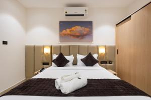 a bedroom with a large bed with two towels on it at ELYSIUM Premier Suites Hitec City in Hyderabad +45 photos
