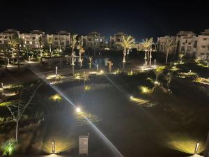 a night view of a park with palm trees and lights at Chalet in north coast in El Dab‘a