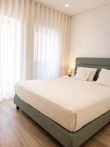 a large bed in a bedroom with white curtains at Casa Candil in Nazaré