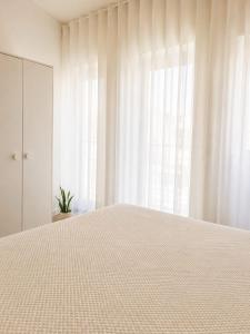 a white bedroom with a large bed and a window at Casa Candil in Nazaré