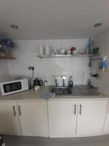 a small kitchen with a sink and a microwave at Inviting 1-Bed Cottage in Pontypridd in Pontypridd