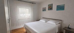 a white bedroom with a bed and a window at Apartment Nereo in Senj