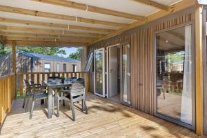 a wooden deck with a table and chairs on it at Mobilehome Evasion 55 in Saint-Gervais