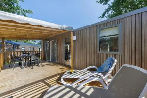 a wooden deck with a table and chairs on it at Mobilehome Evasion 55 in Saint-Gervais
