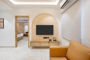 a living room with a couch and a tv on a wall at ELYSIUM Premier Suites Hitec City in Hyderabad
