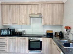 a kitchen with wooden cabinets and a stove top oven at Kairos Guest House in Maseru +5 photos