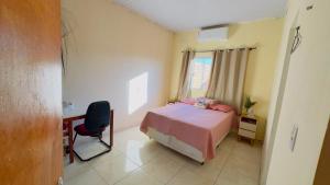 a bedroom with a bed and a desk and a window at Casa da Daniella in Conceição do Araguaia