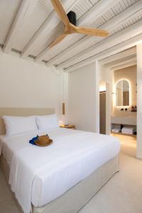 a bedroom with a large white bed with a hat on it at Archipelago Sifnos - Seaside Accommodation in Vathi