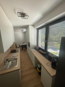 a kitchen with a sink and a desk with a window at Apartmán Formula Trenčín in Trenčín