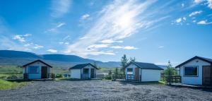 a group of three houses on a gravel road at Bakkaflöt Guesthouse in Varmahlid