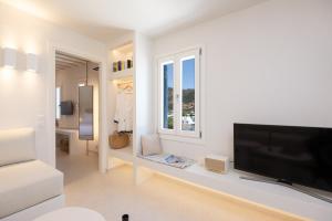 a white living room with a flat screen tv at Archipelago Sifnos - Seaside Accommodation in Vathi