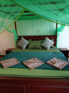 a green bed with two towels on top of it at Rainforest Nature Resort - Sinharaja in Deniyaya