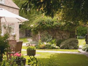 a garden with two chairs and flowers and an umbrella at Saltersgate in Pickering