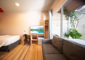 a bedroom with a couch and a desk with a tv at Villa Crescenta in Ukulhas