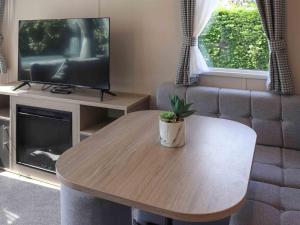 a living room with a coffee table and a television at Sarnfaen Static - Uk52097 in Llanddwywe