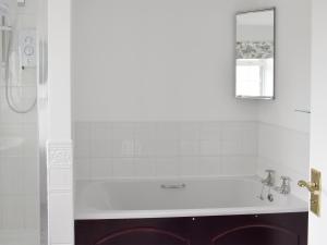 a white bathroom with a tub and a mirror at Rudda Farm Cottage - Uk2492 in Staintondale