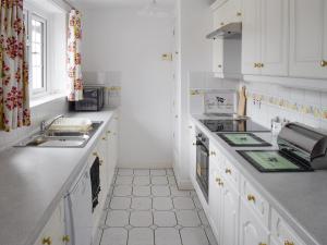 a kitchen with white cabinets and a sink at Rudda Farm Cottage - Uk2492 in Staintondale