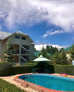 a house and a swimming pool with an umbrella at Алтын Мезгил in Korumdy