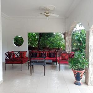 a porch with red chairs and a ceiling fan at Belle villa face au lac in Sokone