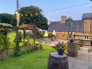 a garden with a patio and a house with lights at The Boyne Arms Cottage in Burwarton