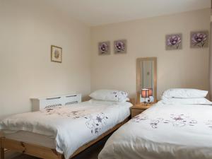 two beds in a room with white walls at Esthwaite in Windermere +1 photo