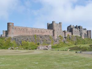 a castle on top of a hill with a grass field at Ebba's Neuk in Beadnell