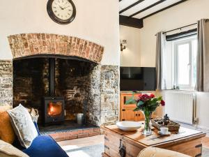 a living room with a stone fireplace with a clock on the wall at The Cottage - Uk35177 in Abbots Bickington