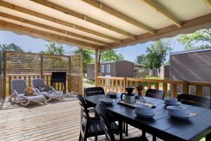 a wooden deck with a black table and chairs at Mobilehome Evasion 46 in Saint-Gervais