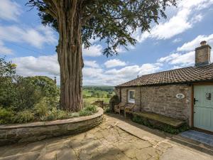 a building with a bench next to a tree at Bloomer's Bothy in Askrigg