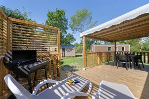 a wooden deck with a grill and chairs on it at Mobilehome Evasion 50 in Saint-Gervais