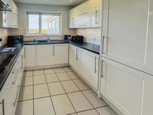 a kitchen with white cabinets and black counter tops at Gramsdale House in Gramisdale