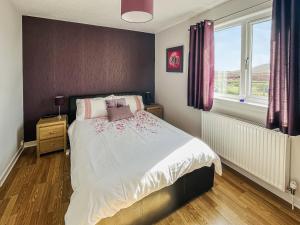 a bedroom with a bed with white sheets and purple curtains at Gramsdale House in Gramisdale +3 photos