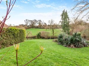 a garden with green grass and trees and bushes at Midsummer Cottage Retreat in Pilton