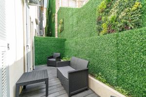 a patio with two chairs and a bench and a green wall at Maison Astéria in Nice