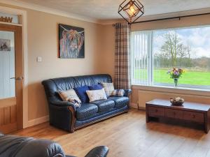 a living room with a leather couch and a window at Seven Seasons in Caldercruix