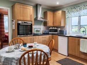 a kitchen with a table and chairs and a kitchen with wooden cabinets at Seven Seasons in Caldercruix +14 photos
