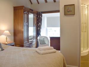 a bedroom with a bed with a chair and a window at Cam Cottage in Kettlewell +11 photos