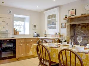 a kitchen with a table and chairs and a kitchen with a fireplace at Cam Cottage in Kettlewell