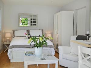 a bedroom with a white bed and a white chair at Petit Knowle in Cuckfield