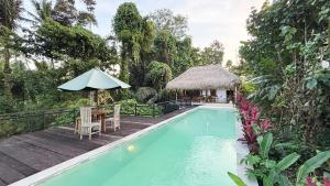 a swimming pool with a table and an umbrella at Amara Giri Ubud View Villas in Ubud