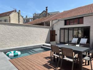 a patio with a table and chairs next to a swimming pool at Appartement avec jacuzzi et piscine sur les remparts in Langres