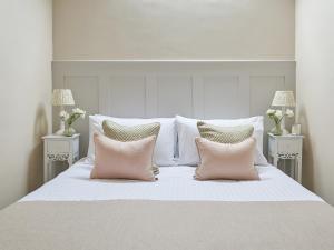a white bed with two pink pillows on it at Farndale in Pickering +3 photos