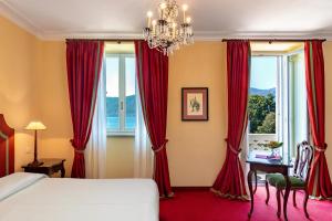 a bedroom with red curtains and a bed and a window at Grand Hotel Majestic in Verbania