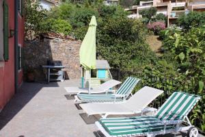 a row of lounge chairs with a green umbrella at La bastide in Vallauris