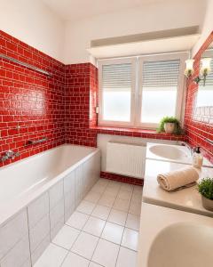 a bathroom with a tub and a sink and red tiles at Appartement in Mönchengladbach 2 Zimmer in Mönchengladbach